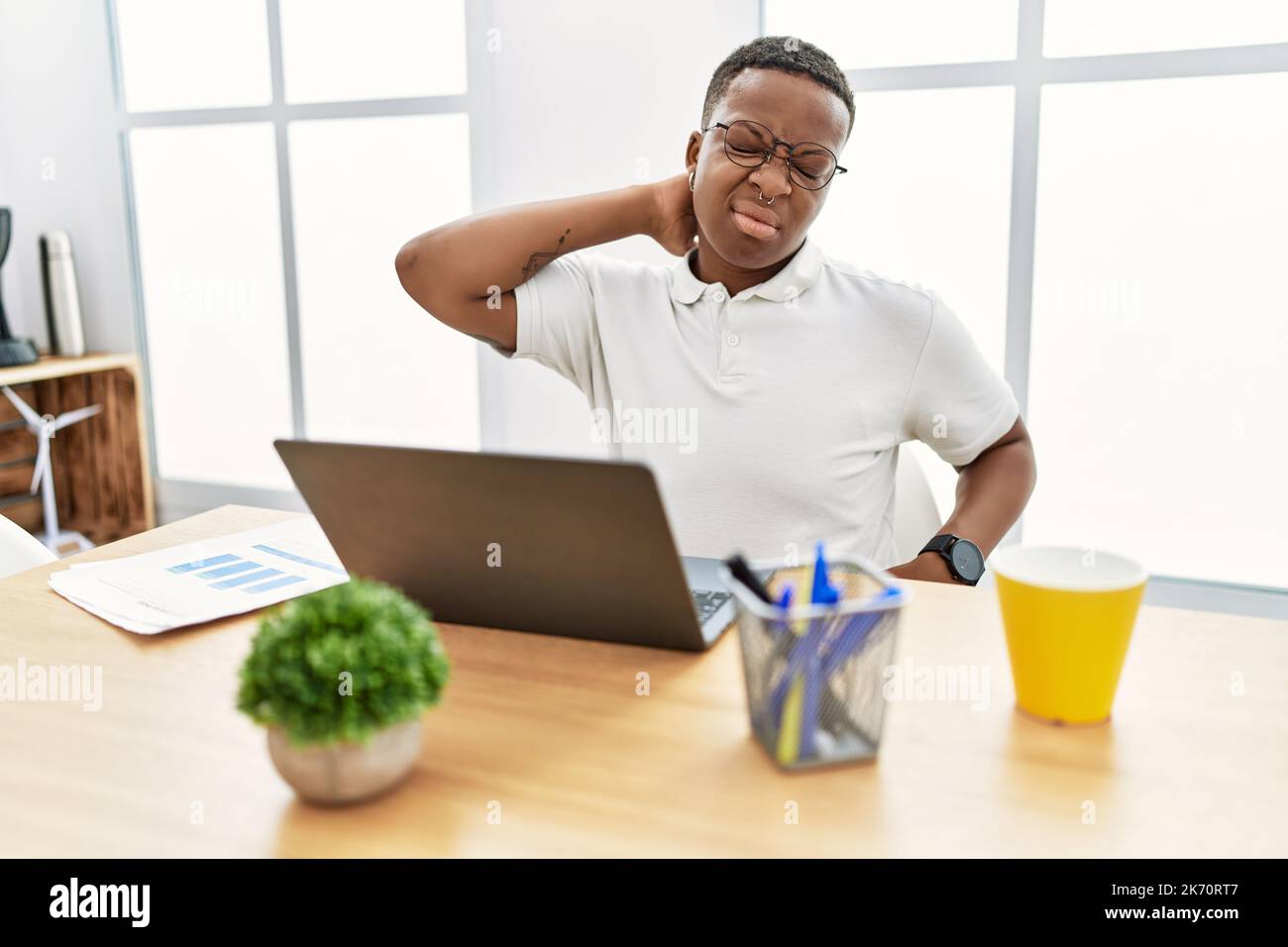 Young african man working at the office using computer laptop suffering ...