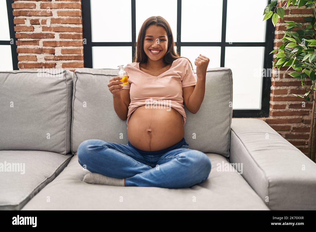 very young pregnant Young pregnant woman holding moisturizer oil to hydrate belly screaming  proud, celebrating victory and success very excited with raised arm Stock  Photo - Alamy