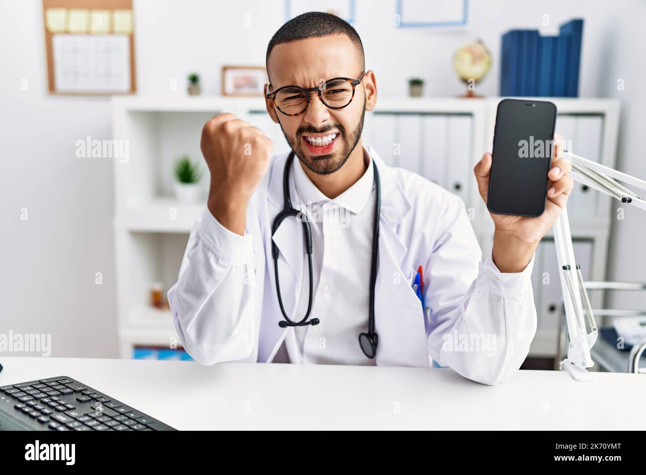 African american doctor man holding smartphone showing blank screen at ...