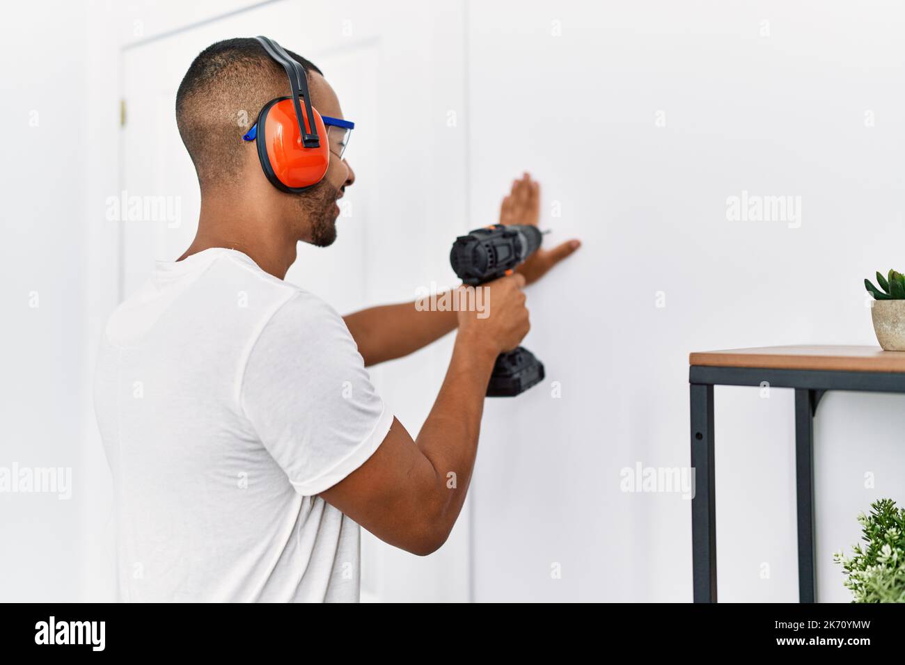 Young hispanic man smiling confident using drill at home Stock Photo