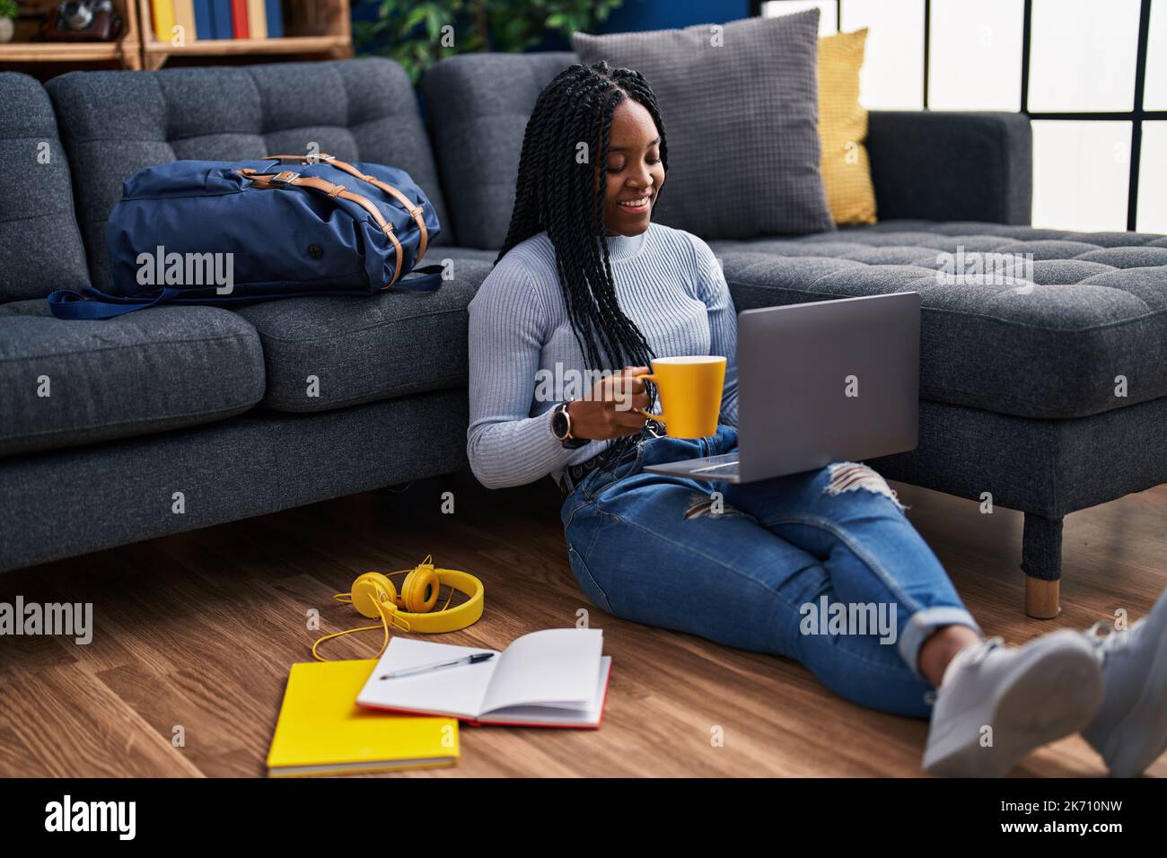 African american woman student using laptop drinking coffee at street ...