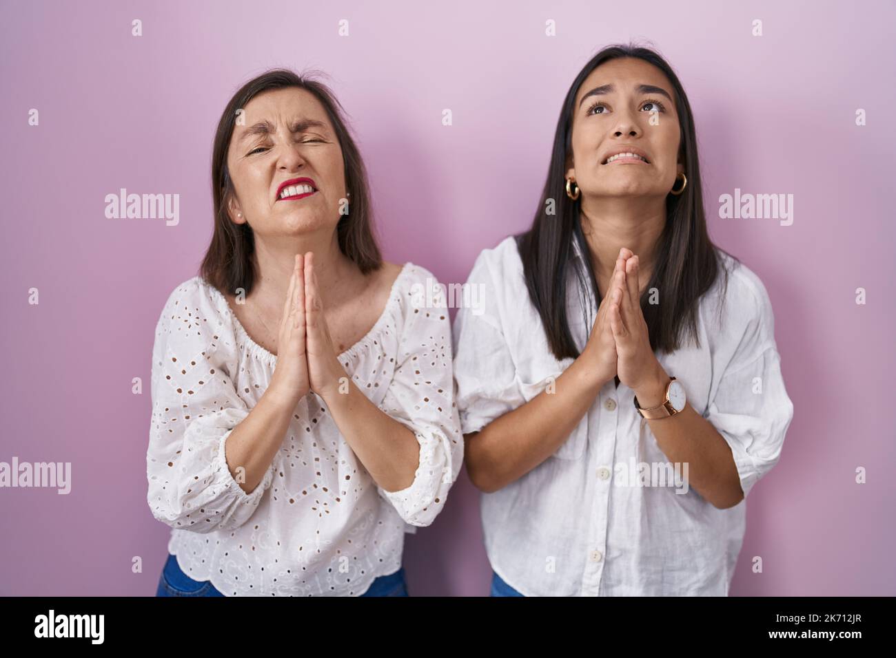 Hispanic mother and daughter together begging and praying with hands ...