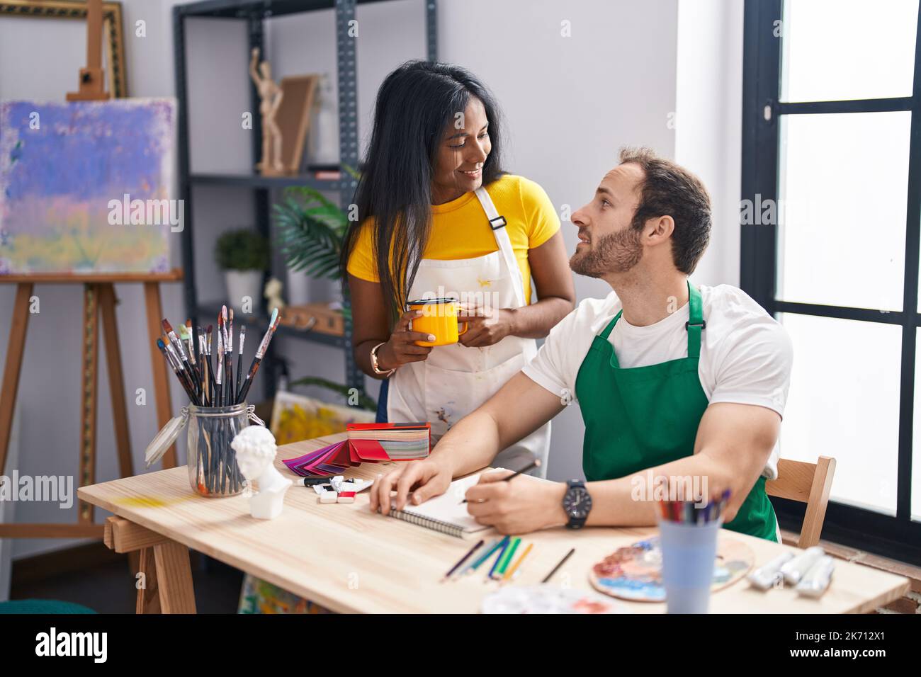 Man and woman artist couple drawing on notebook and drinking coffee at ...