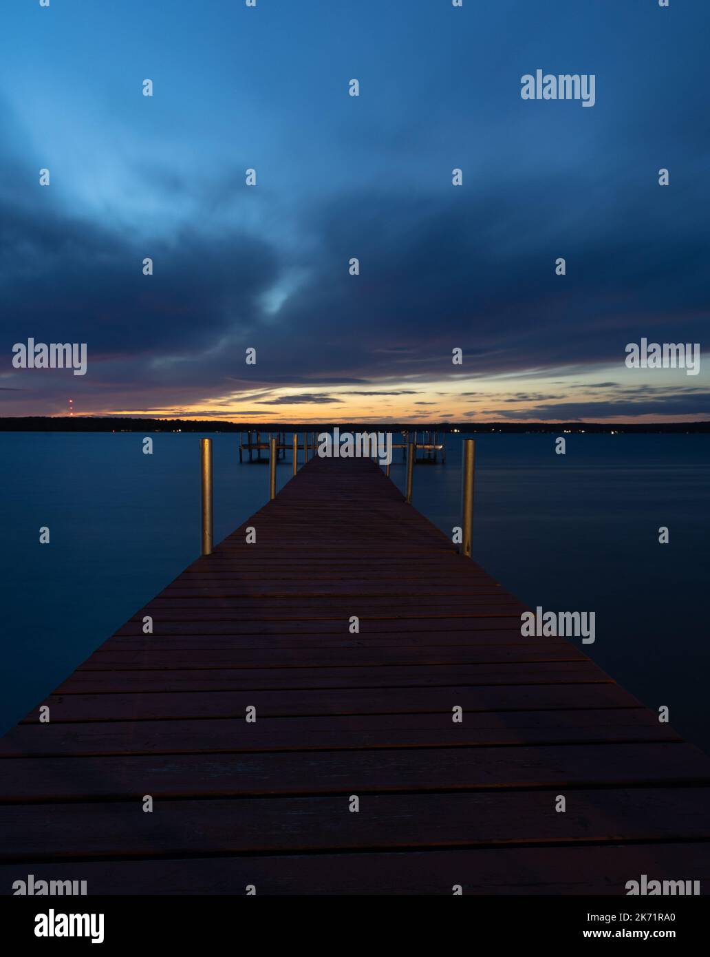 Dock leading out into a lake at sunset Stock Photo