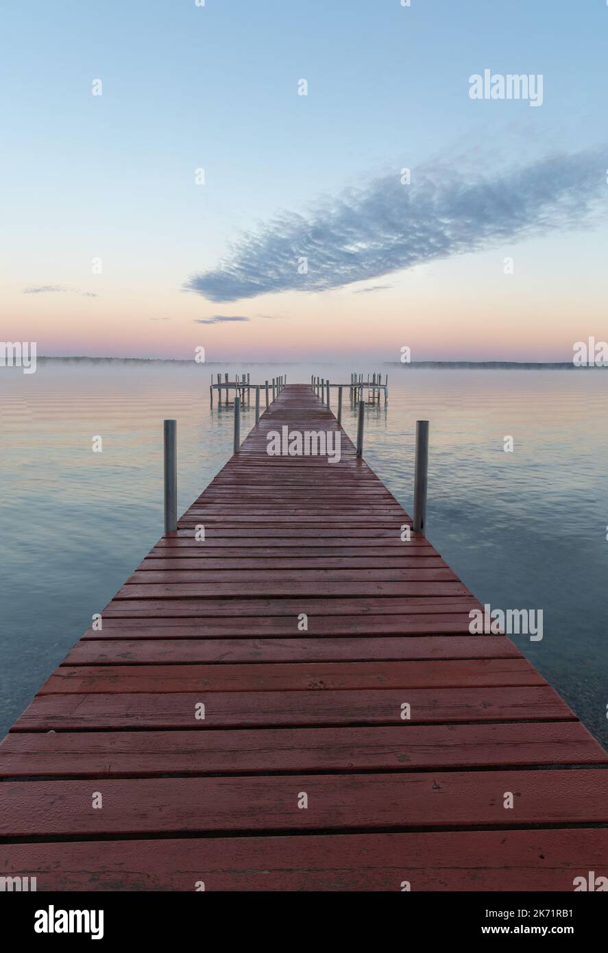 Dock leading out into a lake at sunset Stock Photo