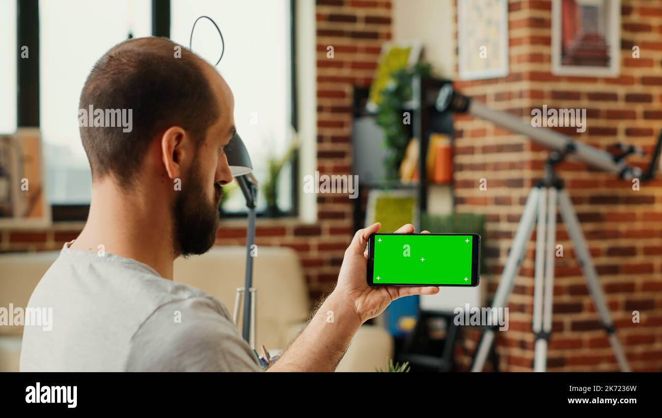 Male employee checking horizontal greenscreen display on mobile phone ...