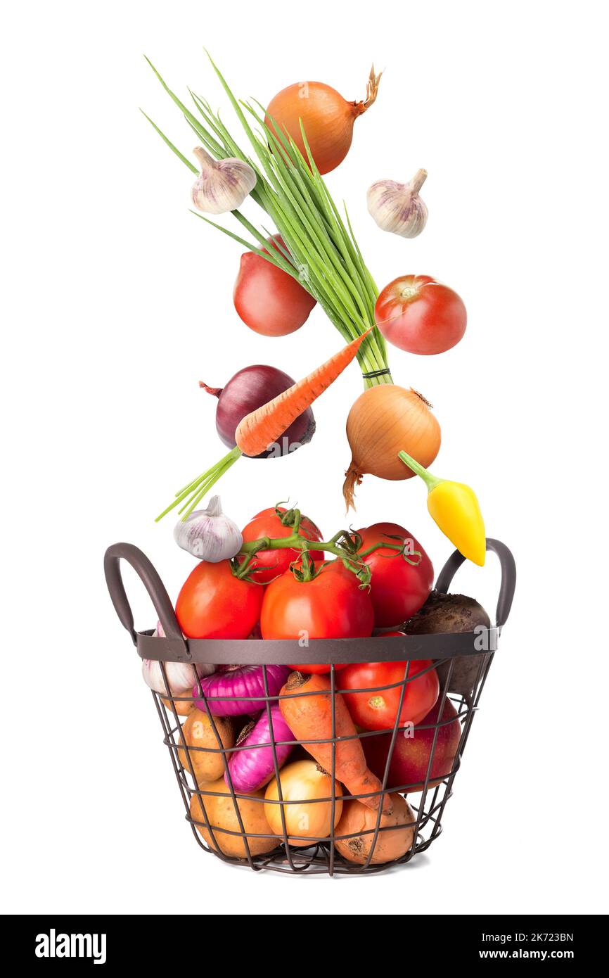 Many healthy vegetables falling into basket on white background Stock Photo