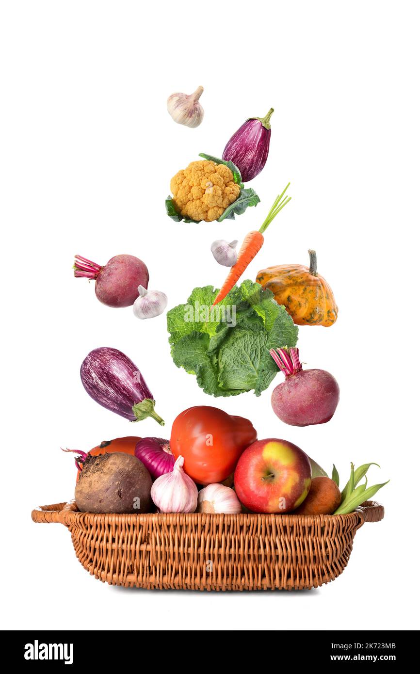 Many healthy vegetables falling into basket on white background Stock Photo
