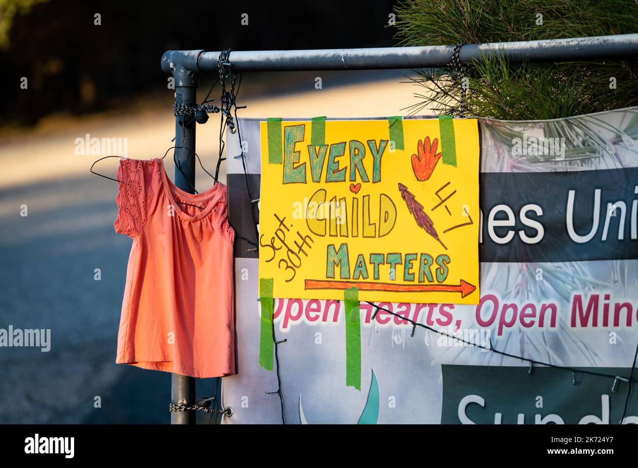 An orange shirt hangs with a sign for an Every Child Matters, Orange Shirt Day event. The event drew attention to Indian boarding schools. Stock Photo