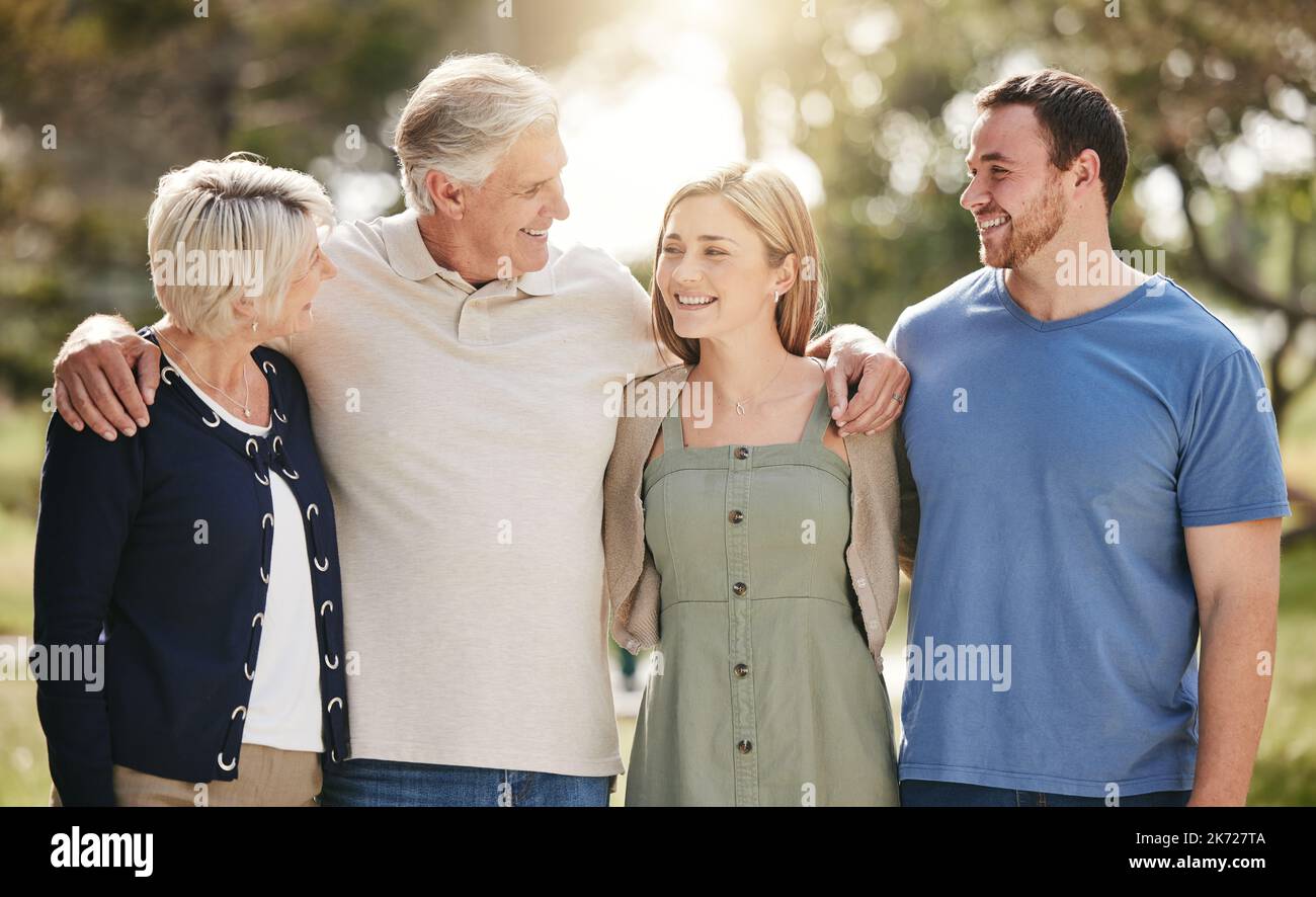 Happy loving caucasian family with adult children standing together in nature on a sunny day. Happy senior couple posing outdoors with their daughter Stock Photo