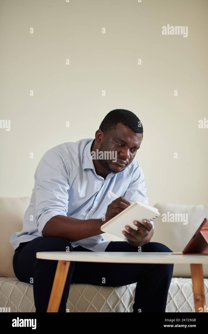 Serios businessman taking notes in planner when attending online meeting Stock Photo