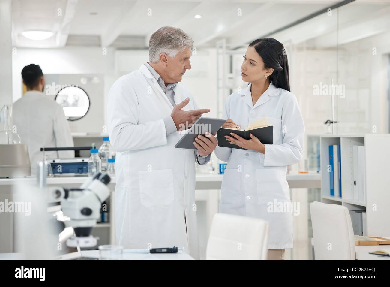 Discussing the new data recorded. two scientists using a digital tablet together in a lab. Stock Photo