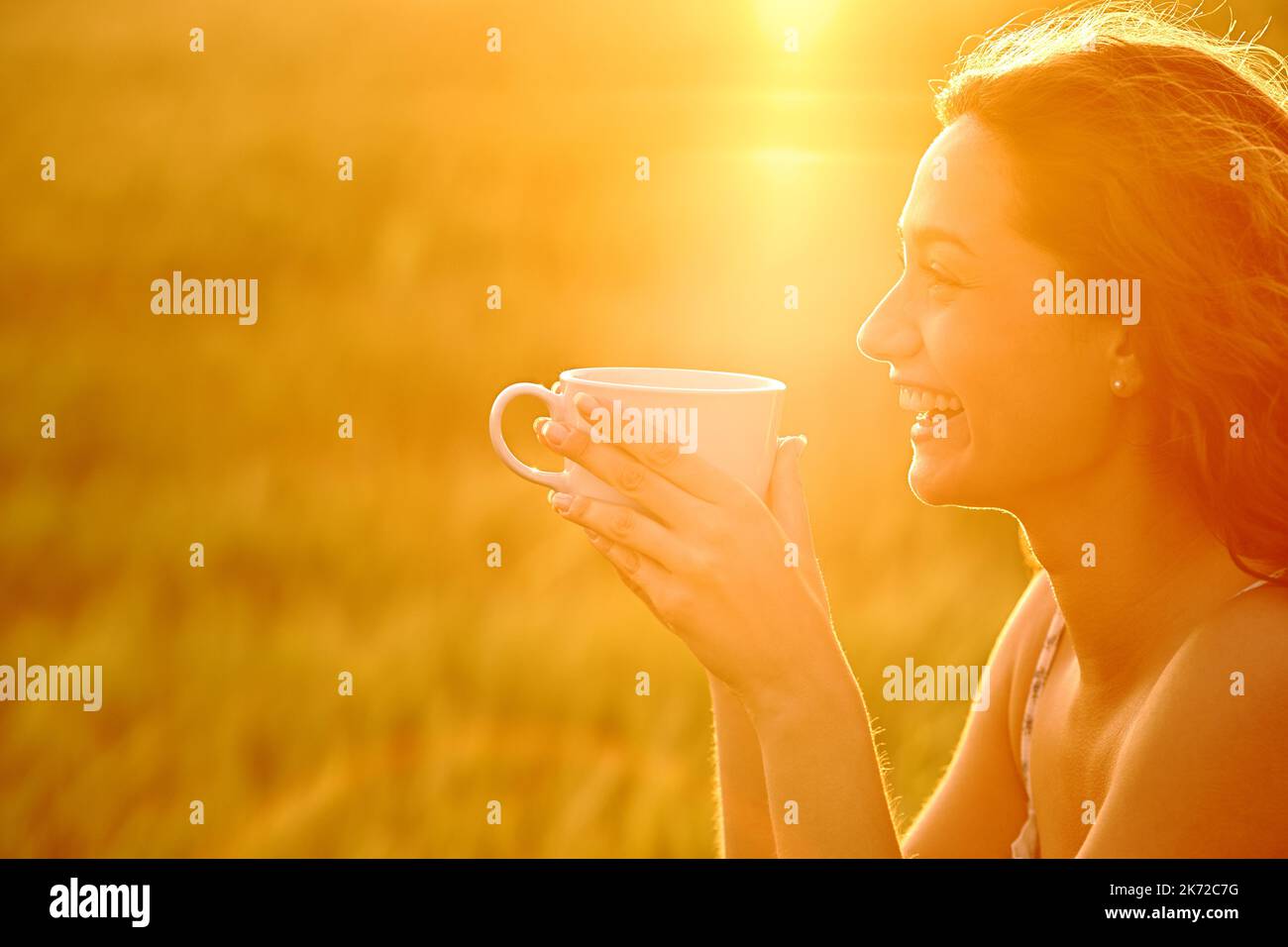 Profile of a happy woman laughing drinking coffee at sunset Stock Photo