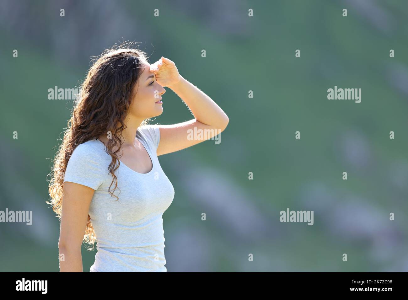Profile of a woman searching with hand on forehead in the mountain Stock Photo