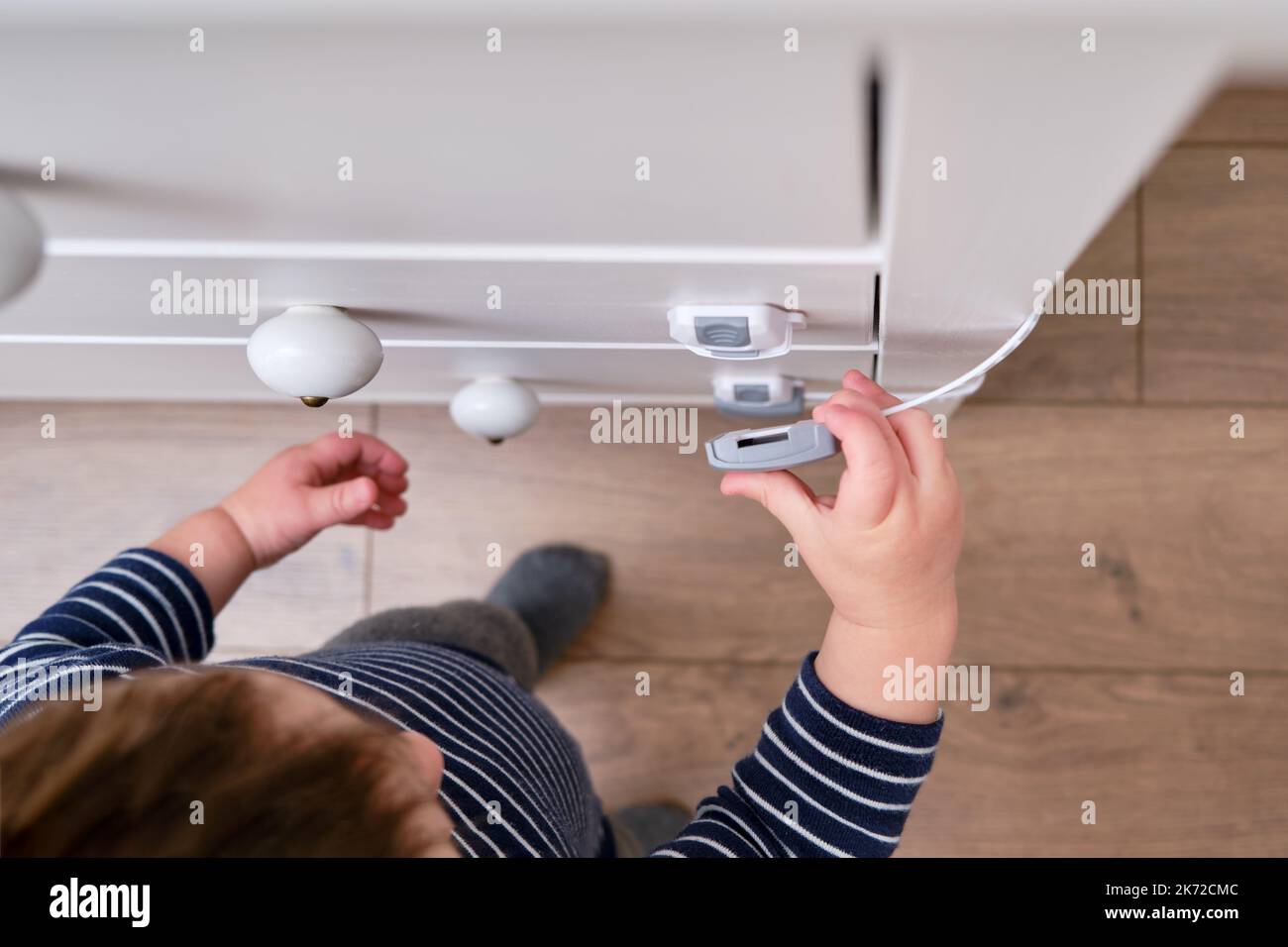 Baby opens the child lock on the closed drawer of the Toddler