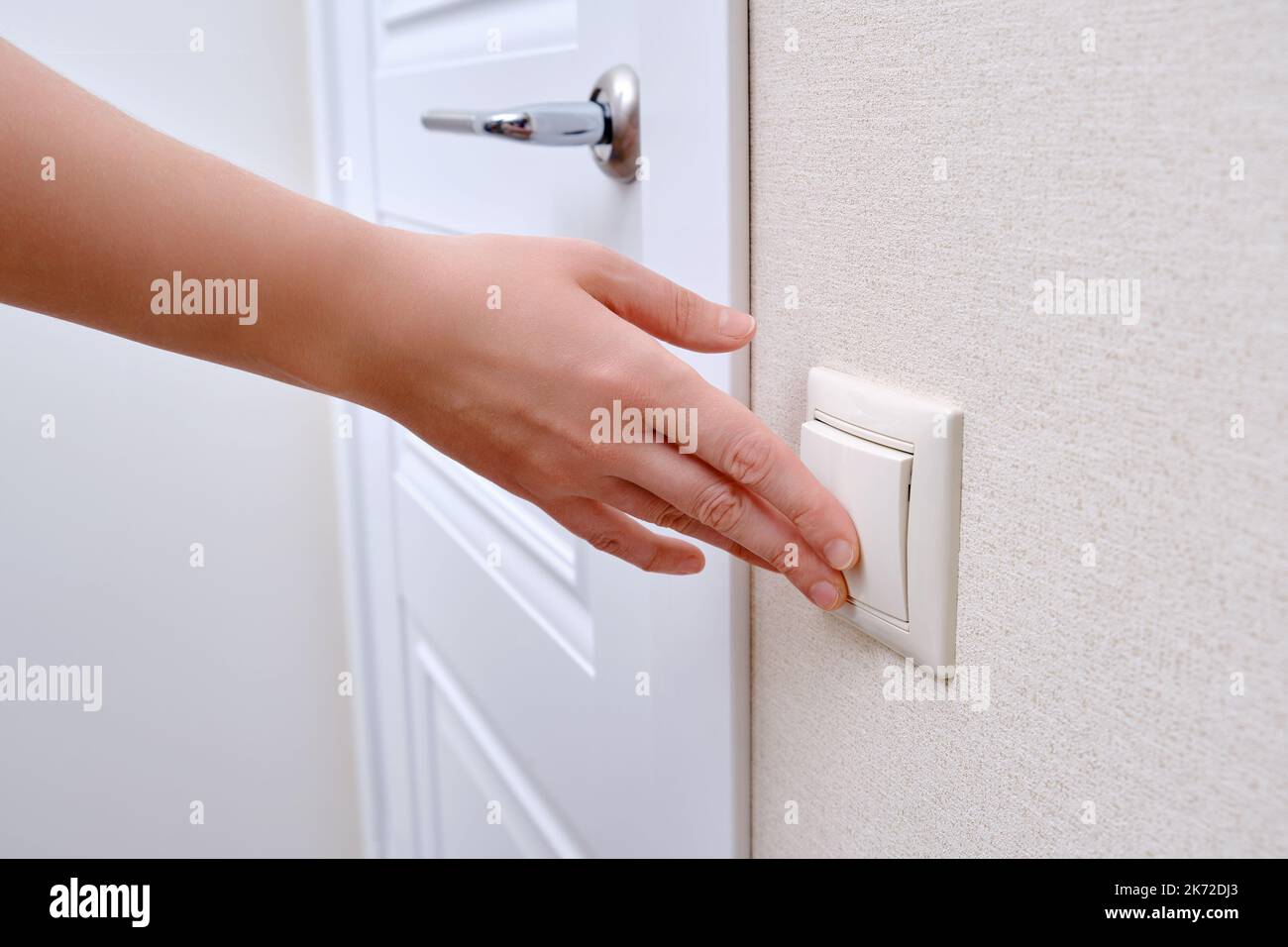 Woman reaches for the light switch, hand turns on the lamp closeup