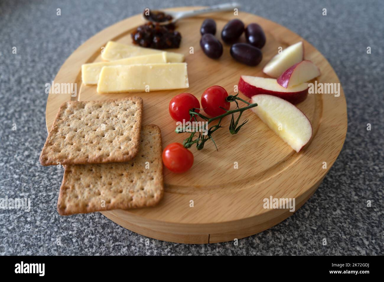 A cheese chopping board with sliced cheese, cherry tomatoes, sliced red