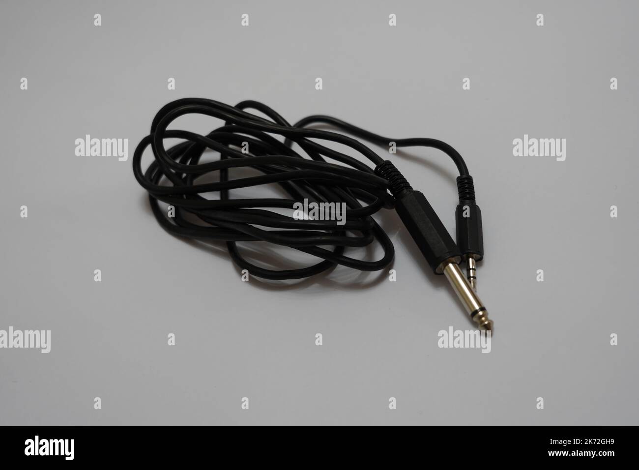 Neatly Coiled Black Audio Cable with 3.5mm Jack on Light Background Stock Photo