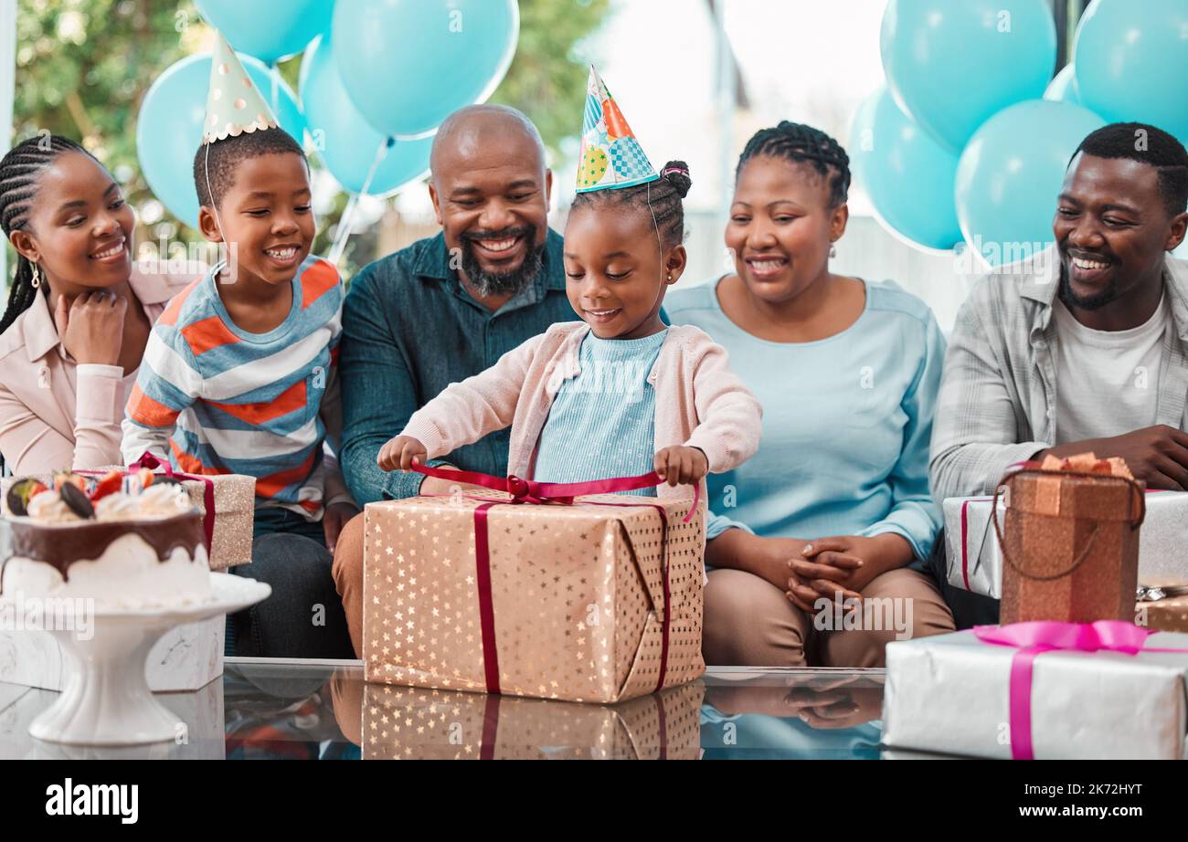 We hope you like your presents. a little girl opening gifts at her birthday party. Stock Photo