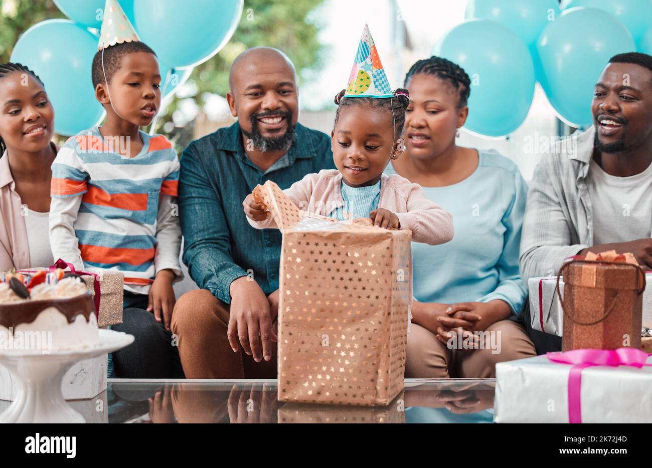 Who got me this one. a little girl opening gifts at her birthday party. Stock Photo