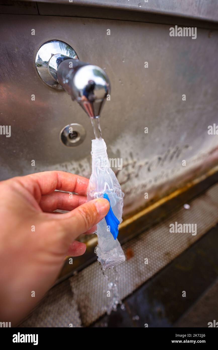 Lourdes, France. September 2, 2022. A pilgrim fills up a Virgin Mary-shape bottle with the Holy Water of Lourdes spring Stock Photo