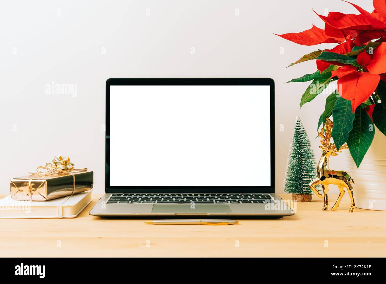 Laptop with mockup blank screen on wooden table with Christmas gift, poinsettia plant flowers on white background. Computer with Mock up and copy Stock Photo