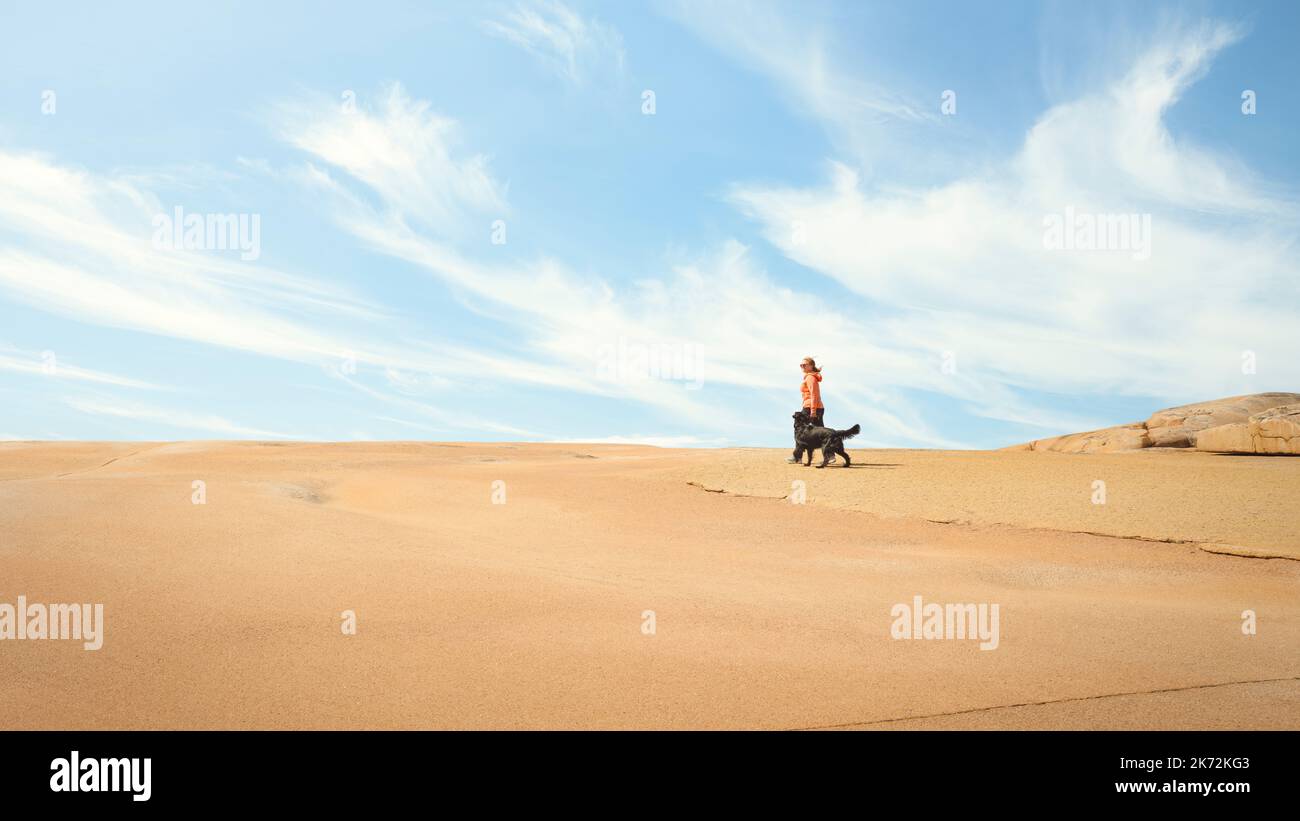 Woman walking dog at sand dune Stock Photo