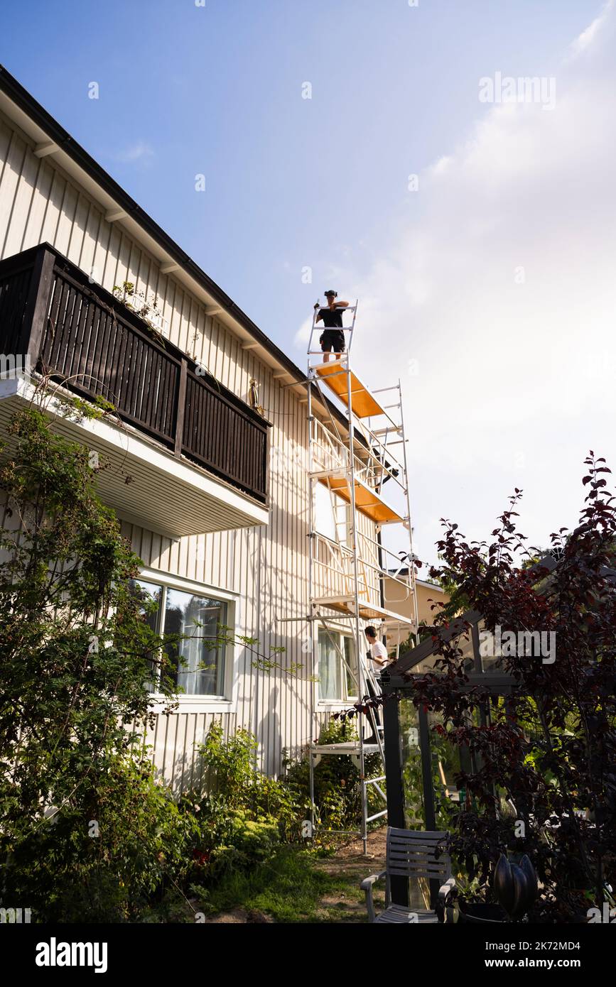 Men on scaffolding renovating house Stock Photo
