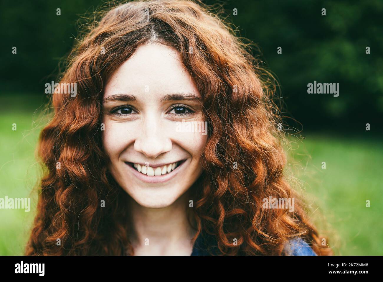 Happy read hair girl smiling on camera outdoor - Focus on face Stock Photo