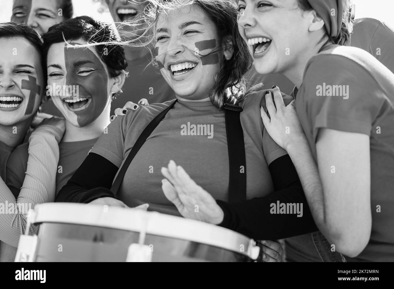 Multiracial red sport football fans screaming while supporting their team - Focus on center girl face - Black and white editing Stock Photo