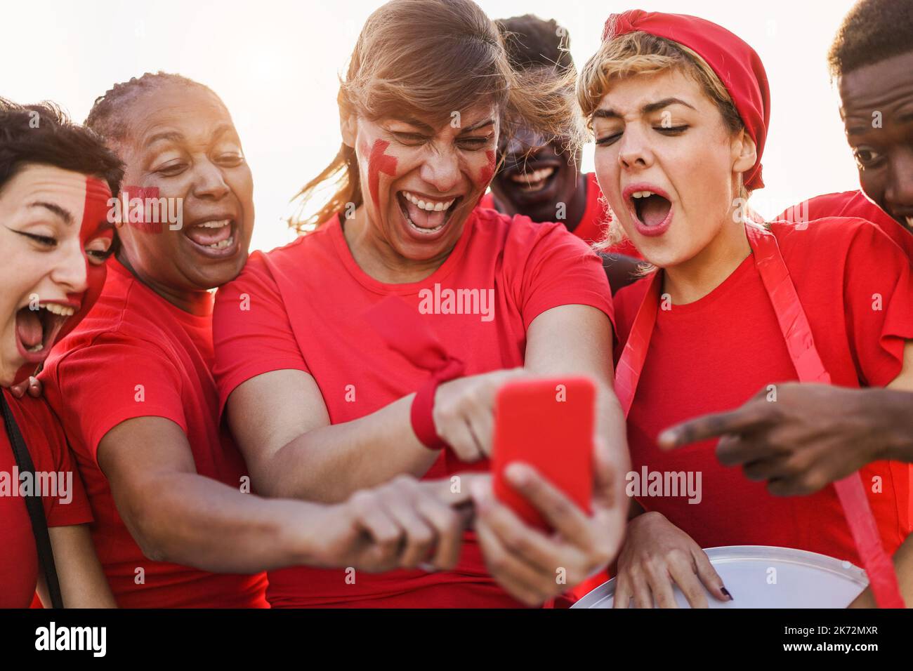Multiracial sport supporters watching football game on mobile phone - Main focus on center woman face Stock Photo