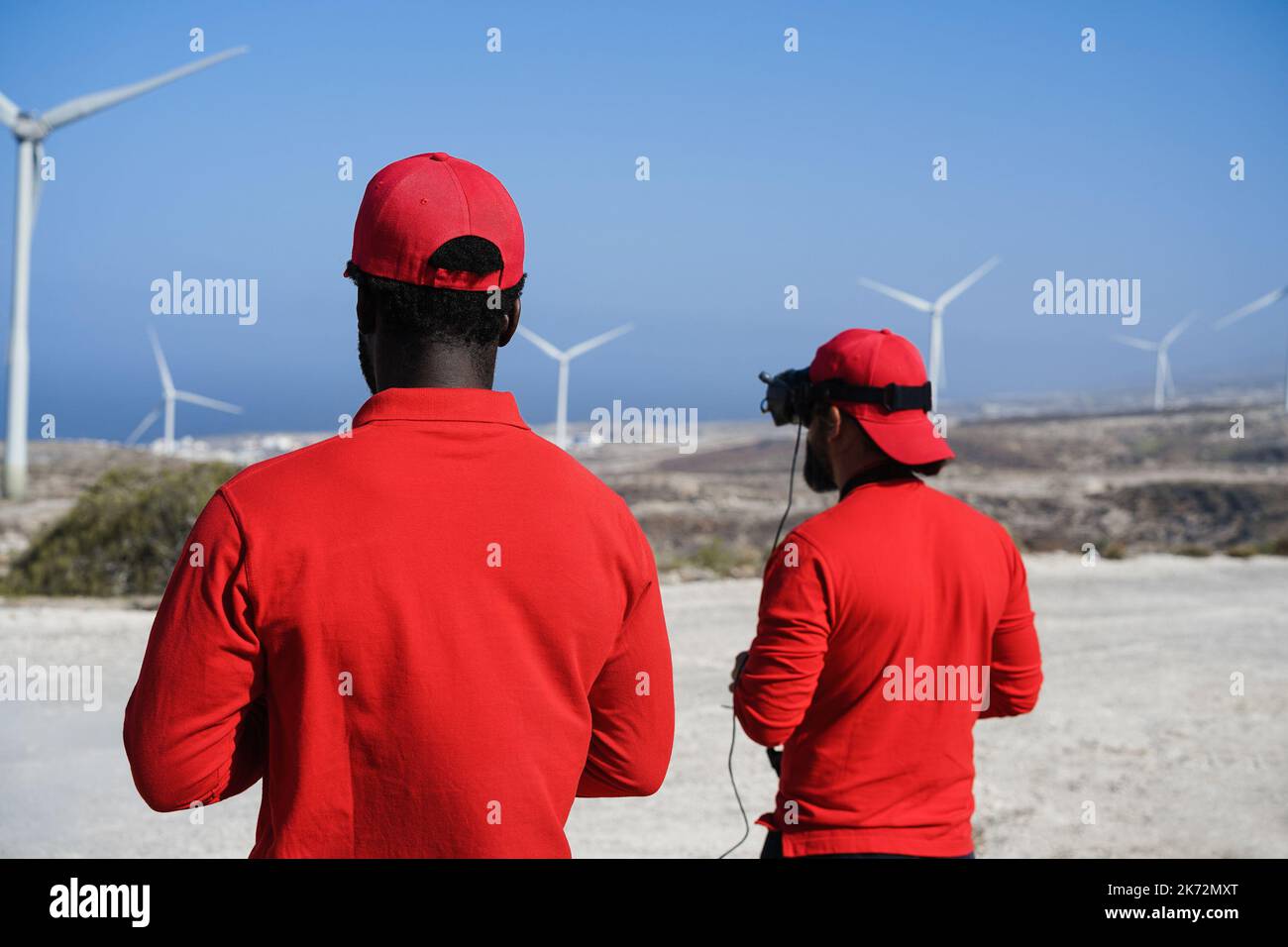 Engineers using virtual reality headset while working at windmill farm - Focus on african man head Stock Photo