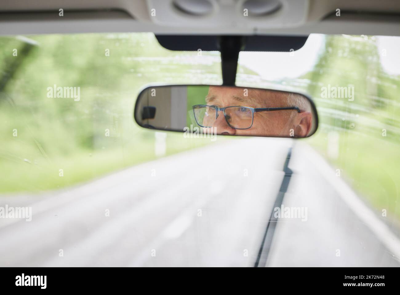 Reflection of senior man in rear-view mirror Stock Photo