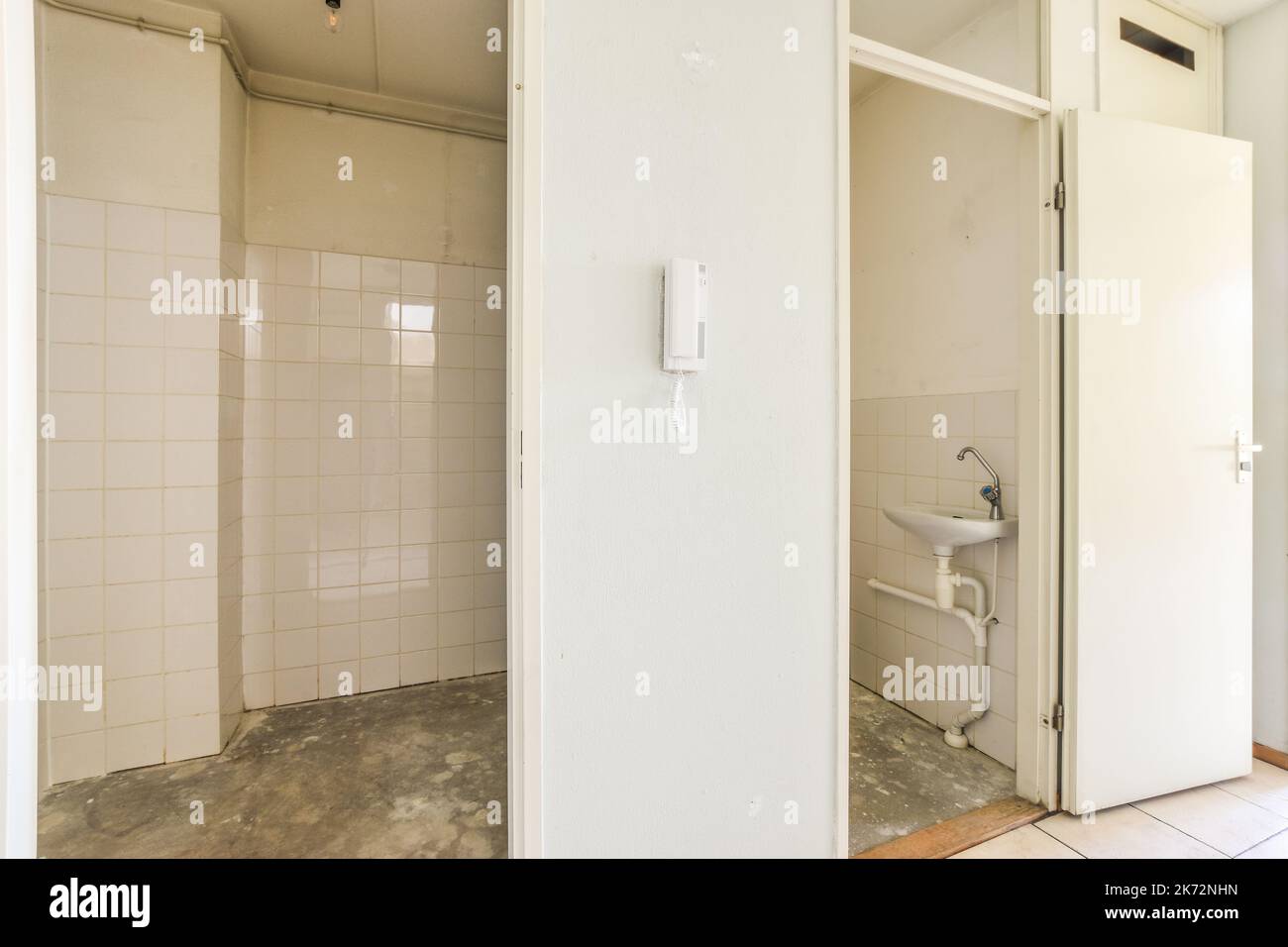 Flush toilet and ceramic sink installed on white tiled walls small