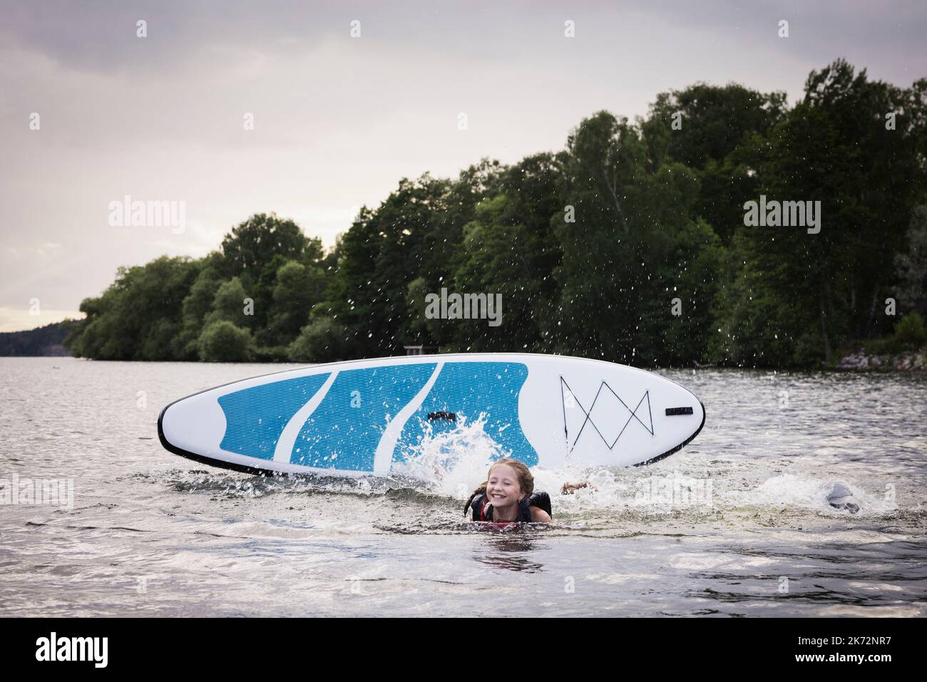 Girl falling from paddle board on lake Stock Photo Alamy