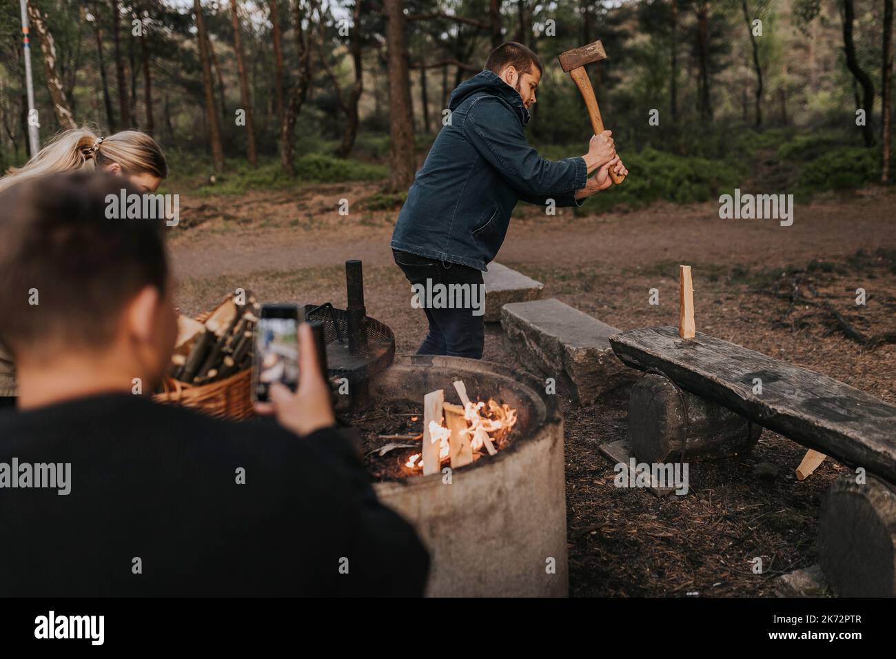 Man taking picture of friend chopping wood Stock Photo