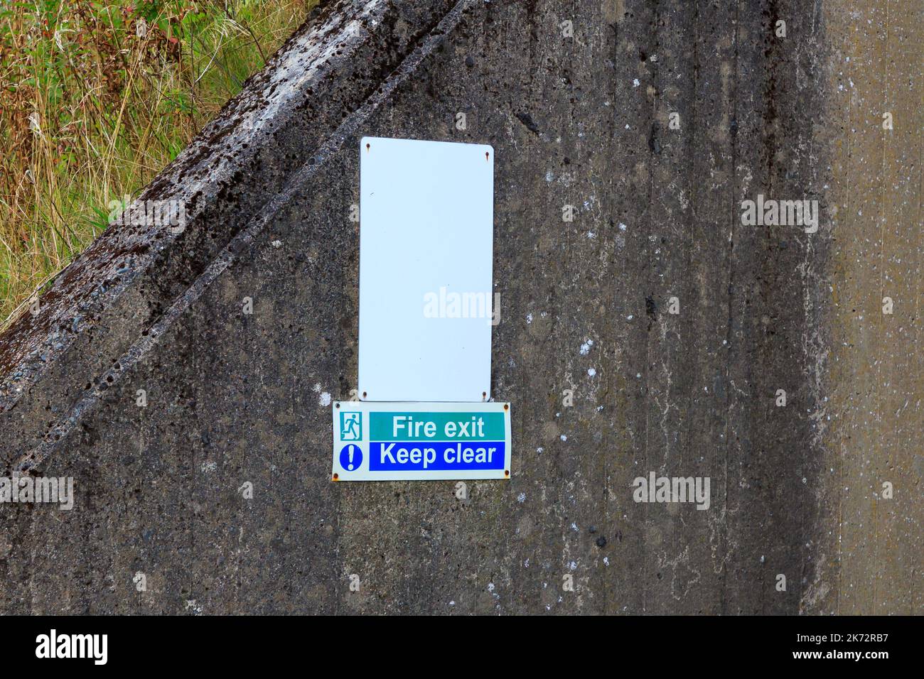Fire exit and keep clear sign fixed to concrete wall Stock Photo
