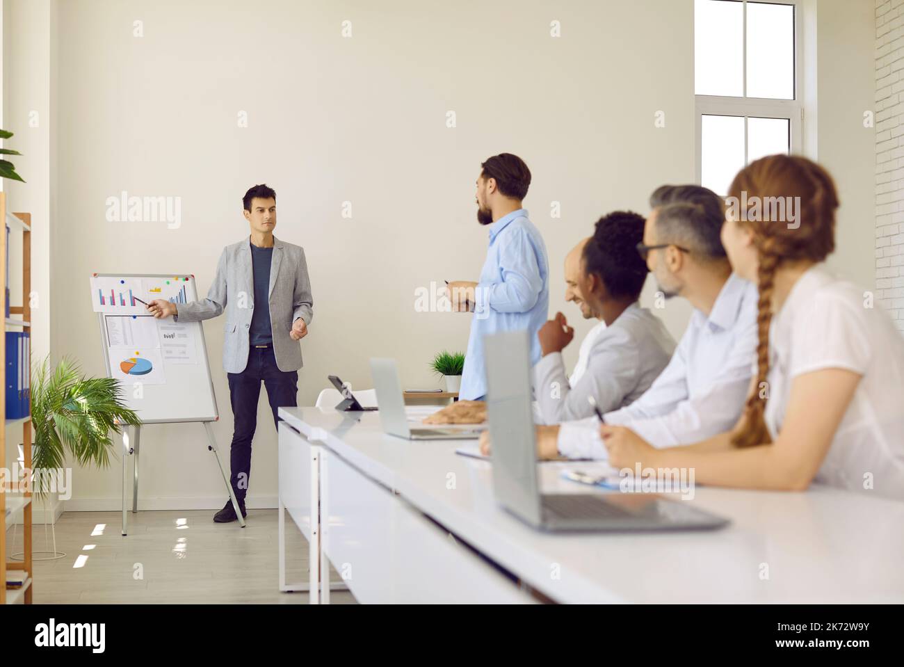 Young man making business presentation in front of office whiteboard during team meeting Stock Photo