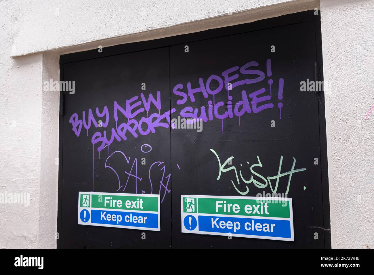 Graffiti scrawled over fire exit doors in Roberts Ope an old alleyway in Truro City centre in Cornwall in the UK. Stock Photo