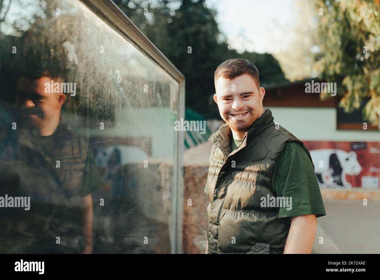 Portrait of caretaker with down syndrome in zoo. Concept of integration people with disabilities into society. Stock Photo