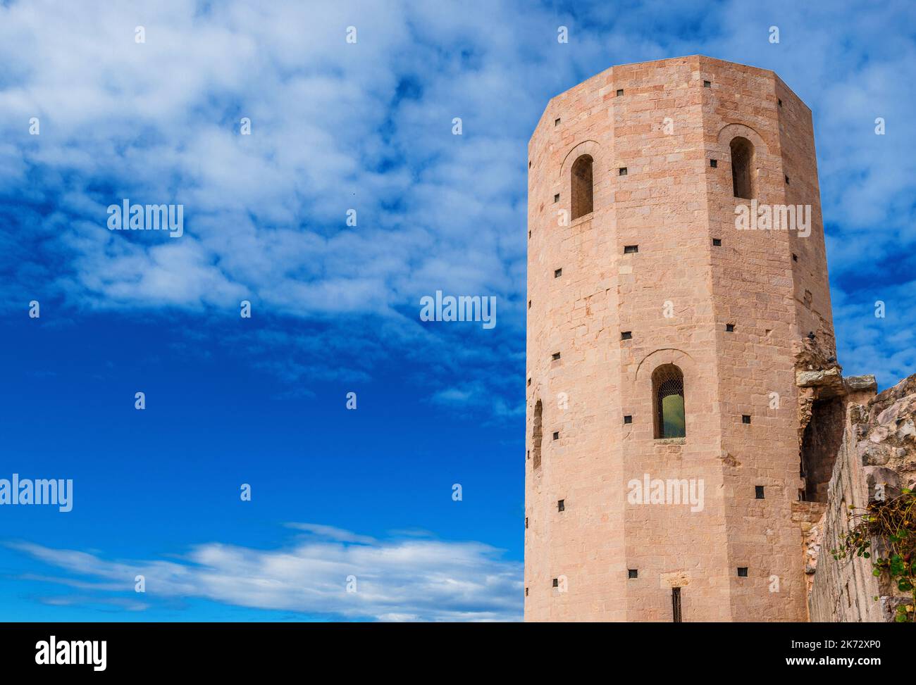 Porta Venere (Venus' Gate) ancient ruins in Spello, with its beautiful dodecagonal tower among white clouds Stock Photo