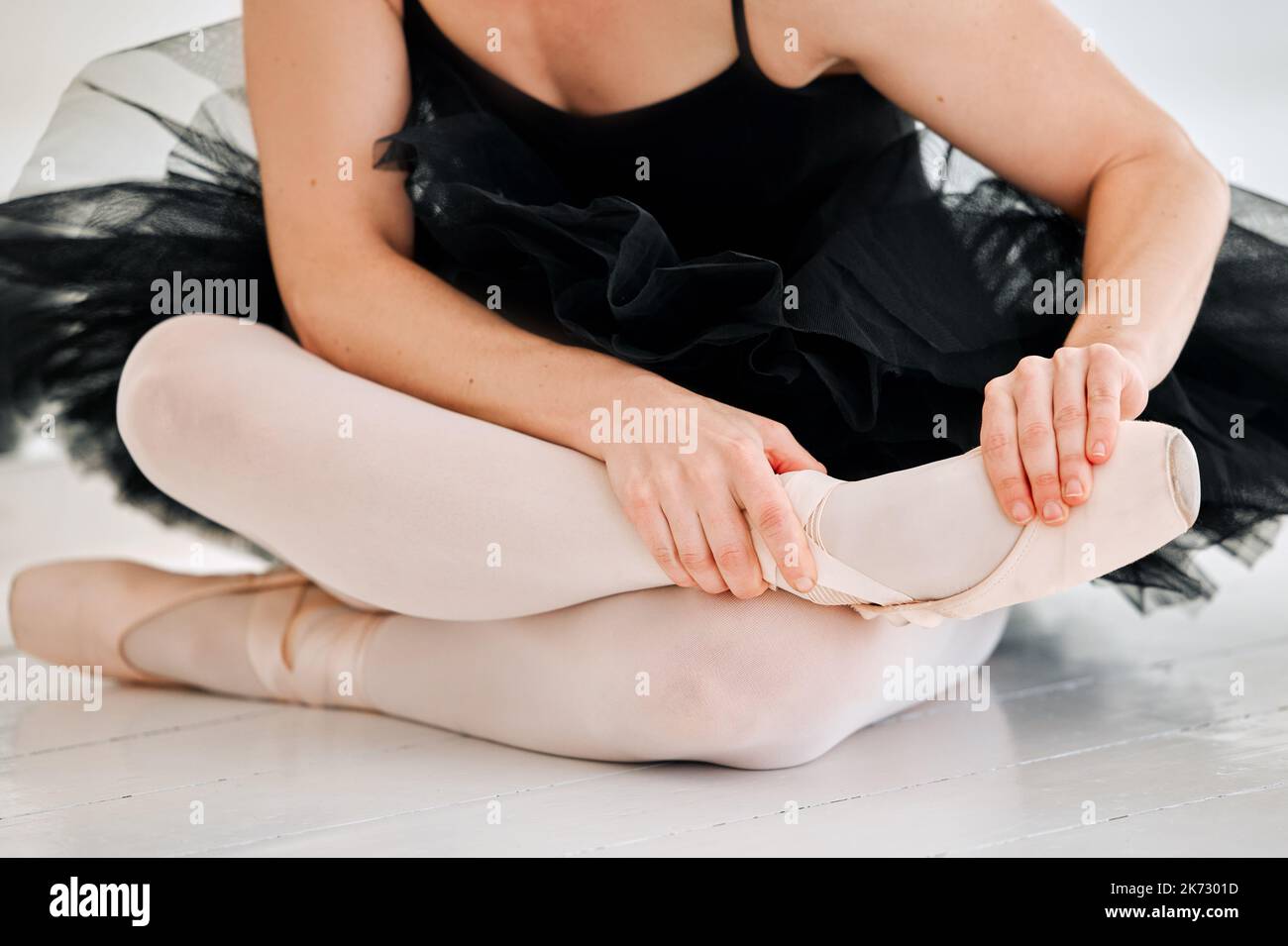 Ballet takes it toll on your feet. an unrecognizable female ballerina rubbing her feet in pain while sitting in the dance studio. Stock Photo