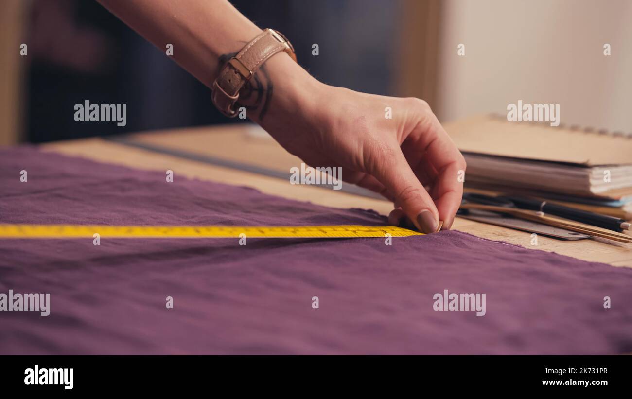 https://c8.alamy.com/comp/2K731PR/cropped-view-of-seamstress-measuring-cloth-near-notebook-on-table-in-atelierstock-image-2K731PR.jpg