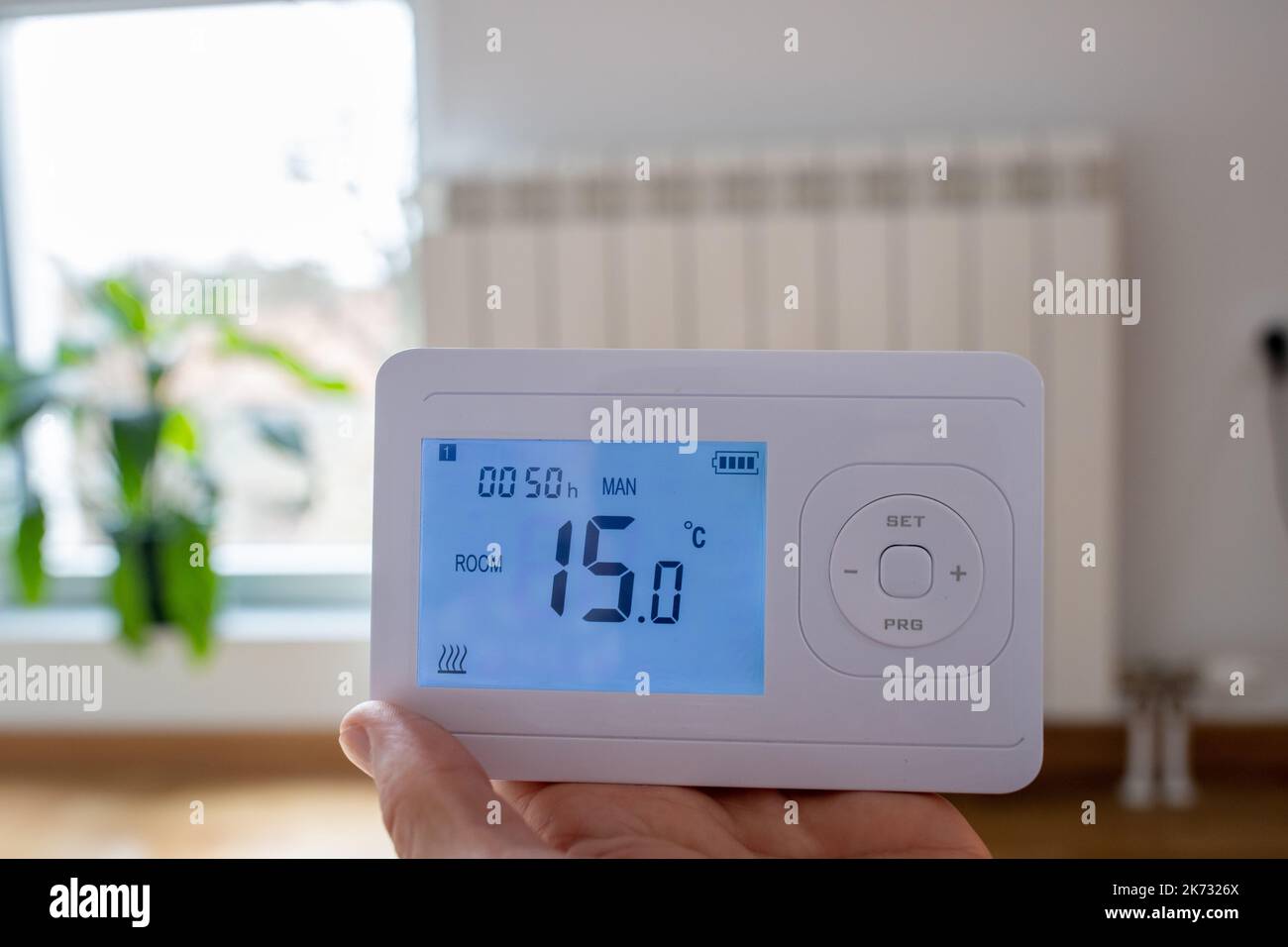 Close up of thermostat heating control panel with heater in background