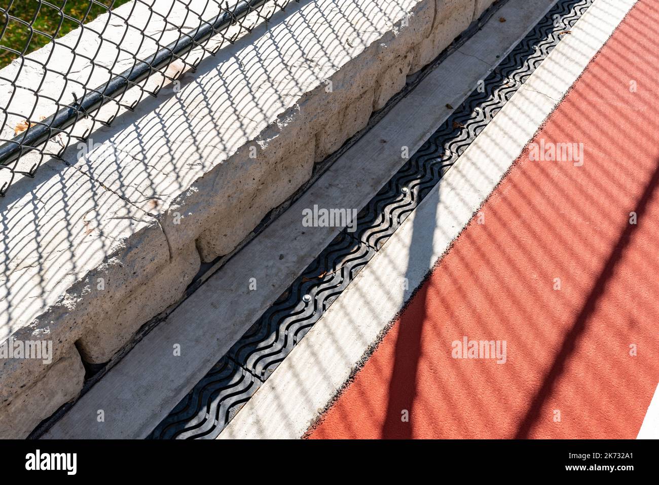 Trench drain along outdoor basketball court at school playground. Stock Photo