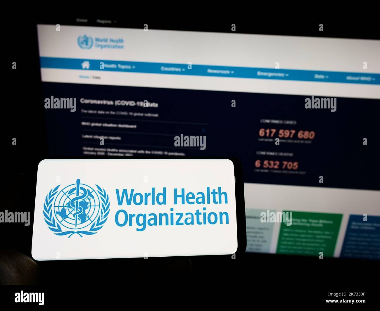 Person holding cellphone with logo of UN agency World Health Organization (WHO) on screen in