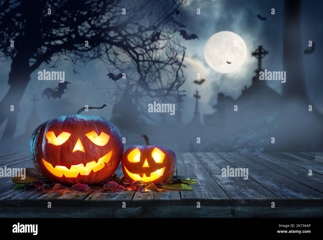 Carved lightening pumpkins for Halloween jack-o'-lanterns with scary smiles to ward of evil spirits on mystery night cemetery background. Halloween ba Stock Photo