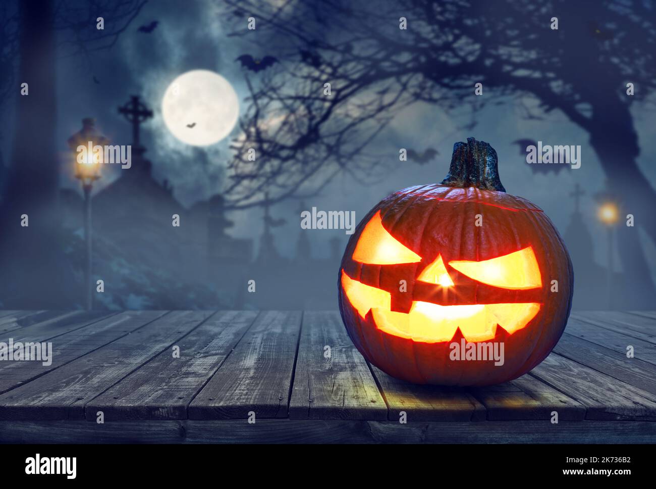 Carved lightening pumpkin for Halloween jack-o'-lanterns with scary smiles to ward of evil spirits on mystery night cemetery background. Halloween bac Stock Photo
