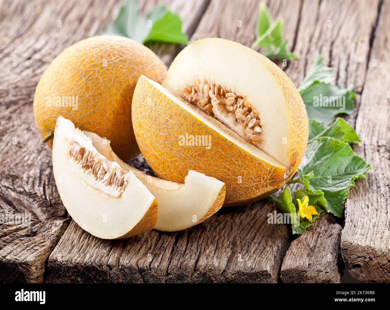 Cantaloupe melon with leaf and melon slice on old wooden table. Stock Photo