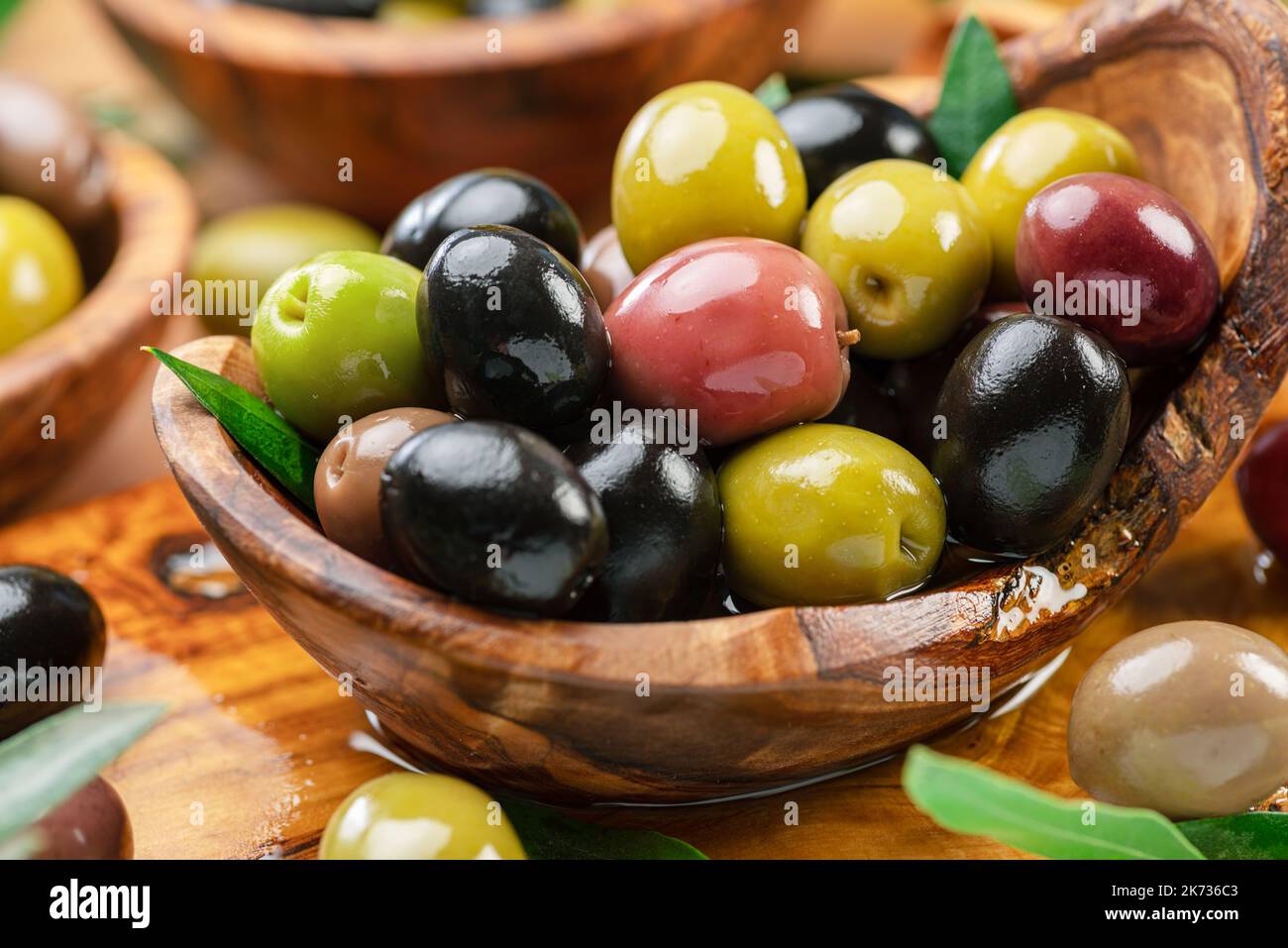 Kalamata, green and black olives in the wooden bowl. Food background. Stock Photo